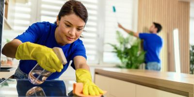 Woman cleaning a kitchen counter with a spray bottle.