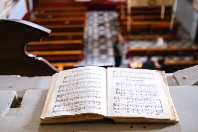 Open sheet music on a wooden ledge inside a church.