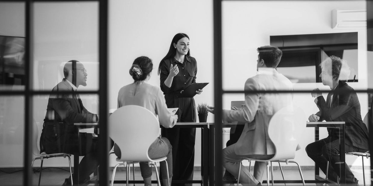Reunión de trabajo con cinco personas en una oficina.
