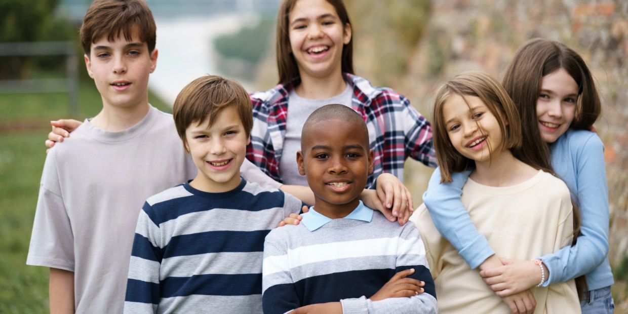 Group of six happy children posing outdoors.