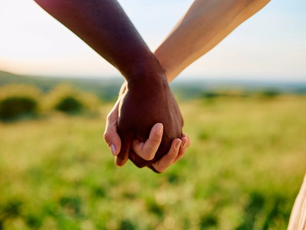 Two people holding hands outdoors.