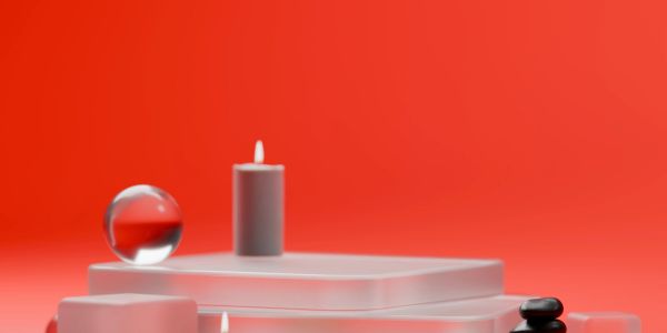 Minimalist display with glass sphere, candle, and stones on frosted platforms.