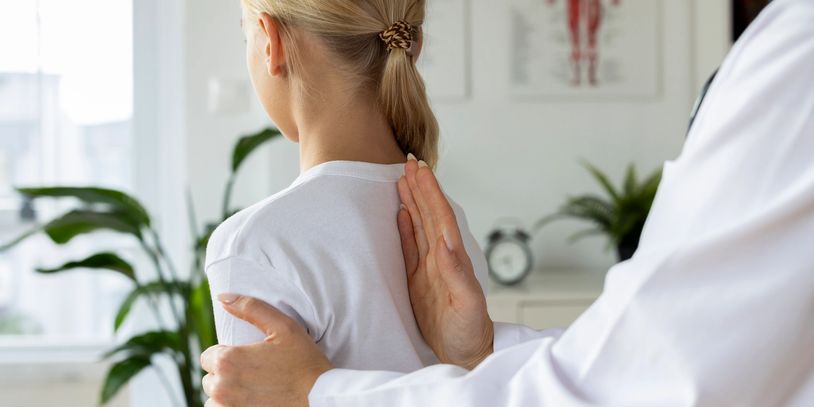 Doctor examining a child's back for spinal health in a clinic.
