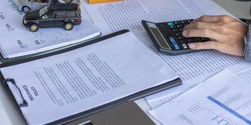 Person calculates figures with documents and a calculator.