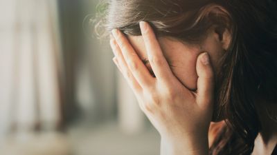 Woman covering her face with her hands in distress.