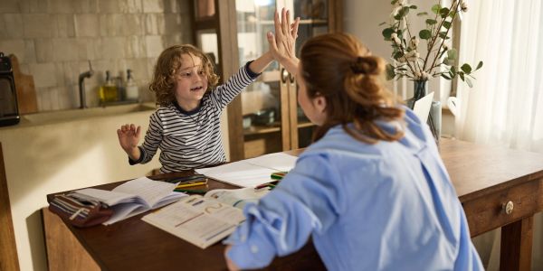Child and adult giving a high-five at a study table.