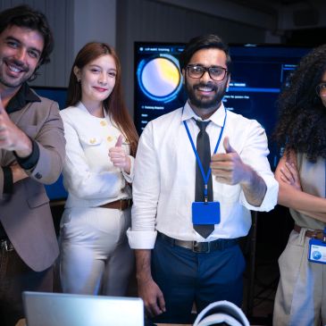 Equipe diverse souriant et faisant un pouce levé au bureau.
