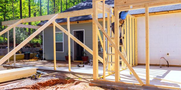 Wooden house frame under construction outside.