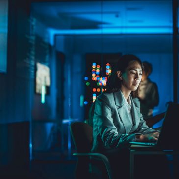 Woman working late on a laptop in a dark room.