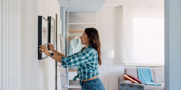 Woman hanging picture frames on a wall.
