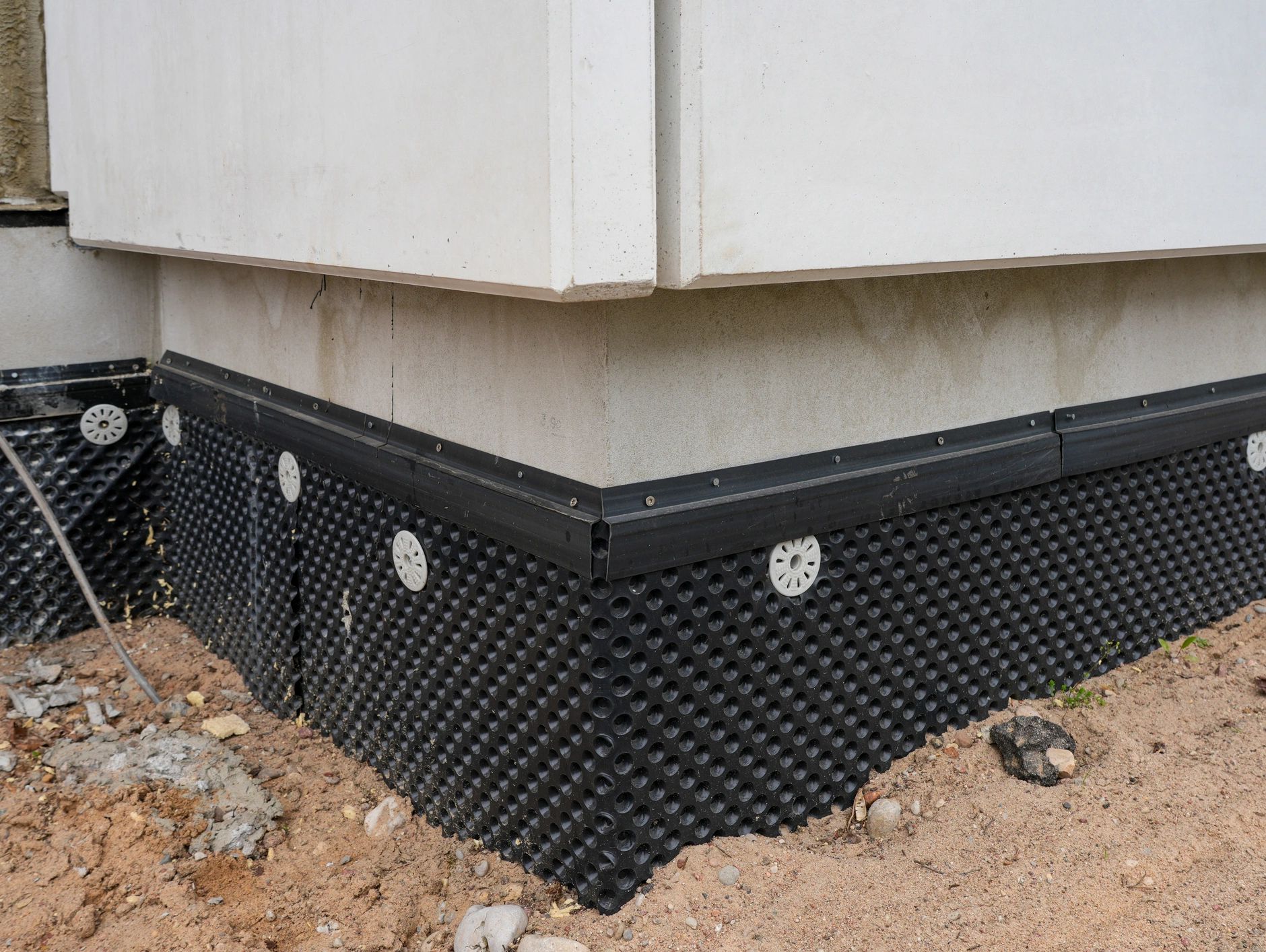 Basement waterproofing barrier installation at building foundation corner.
