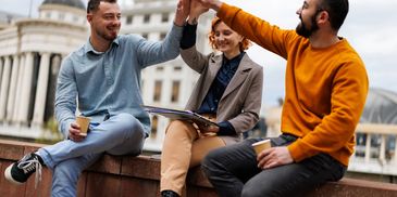 Three friends sharing a high-five outdoors.