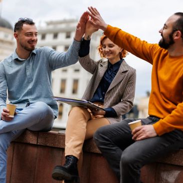 Three friends sharing a high-five outdoors.
