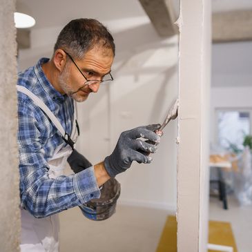 Restoration contractor repairing and finishing drywall during interior reconstruction.