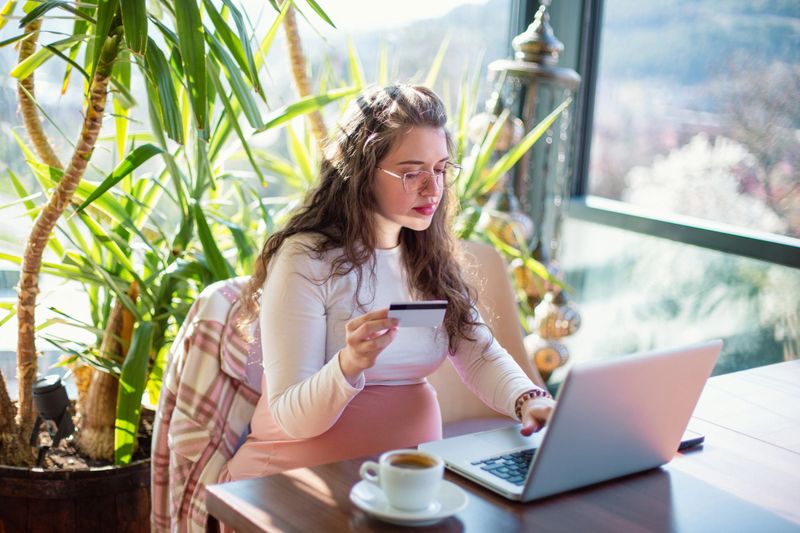 Pregnant woman using laptop and holding credit card for online shopping