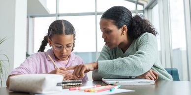 Woman helping girl with homework.