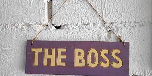 A purple sign reading "THE BOSS" hanging on a white wall.