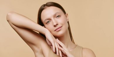Woman with clear skin posing against beige background.