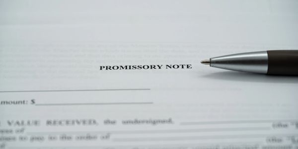Pen resting on a promissory note document.
