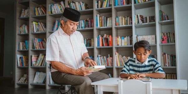Grandfather and grandson reading in a library.