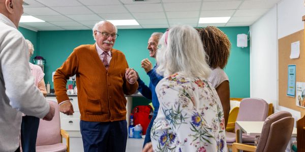 Elderly people dancing and socializing indoors.
