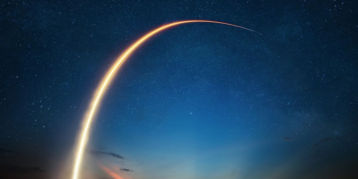 Rocket launch streaking across starry night sky.