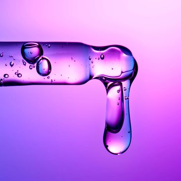 Close-up of a purple liquid droplet on a glass surface.
