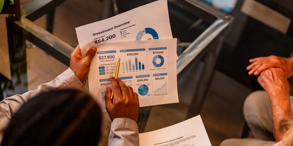 Two people reviewing investment documents with charts and figures.