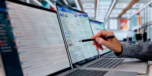 Pessoa interagindo com software em laptops numa estação de trabalho.