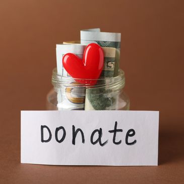 Donation jar with money and red heart.