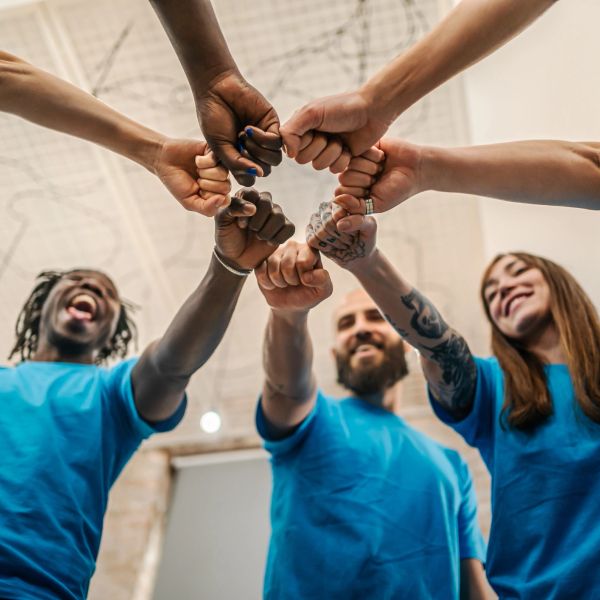 Diverse group doing a group fist bump indoors.