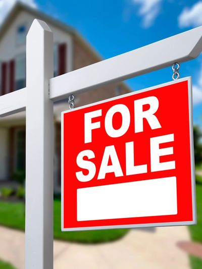 Red for sale sign in front of a house.