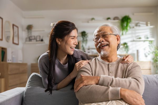 Young woman and elderly man sharing a laugh on a couch.