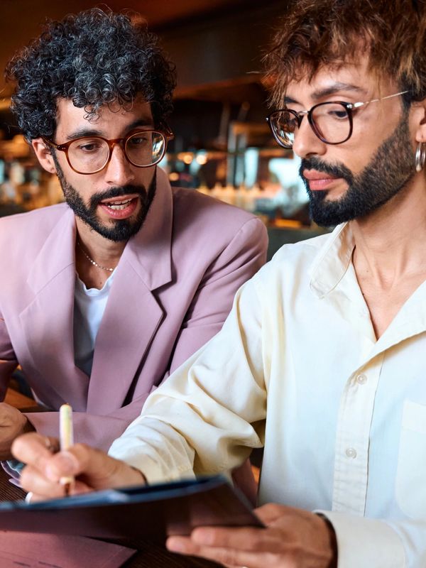 Two men in a cafe, looking at a written document together