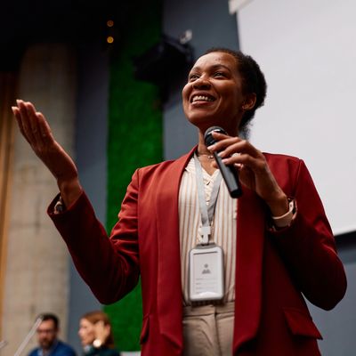 Confident woman speaking with microphone at event.