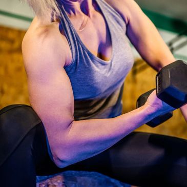 Person lifting a dumbbell to workout arm muscles.