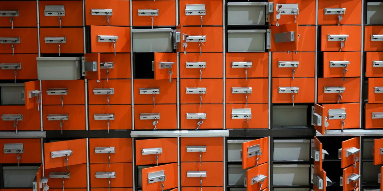 Orange mailboxes with several open and empty slots.