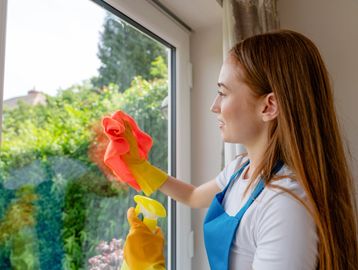 Woman cleaning a window indoors.