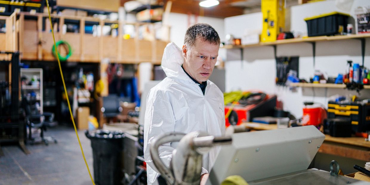 Man in protective suit works in workshop.
