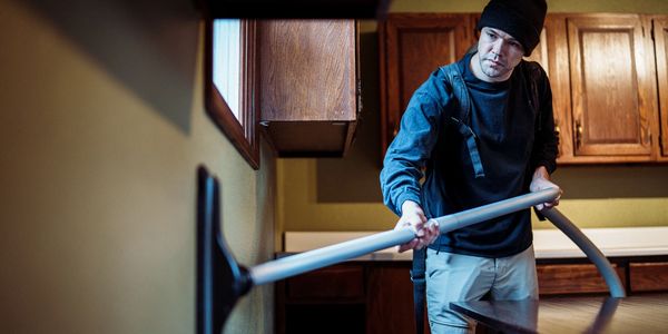 Man cleaning with a vacuum in a kitchen.
