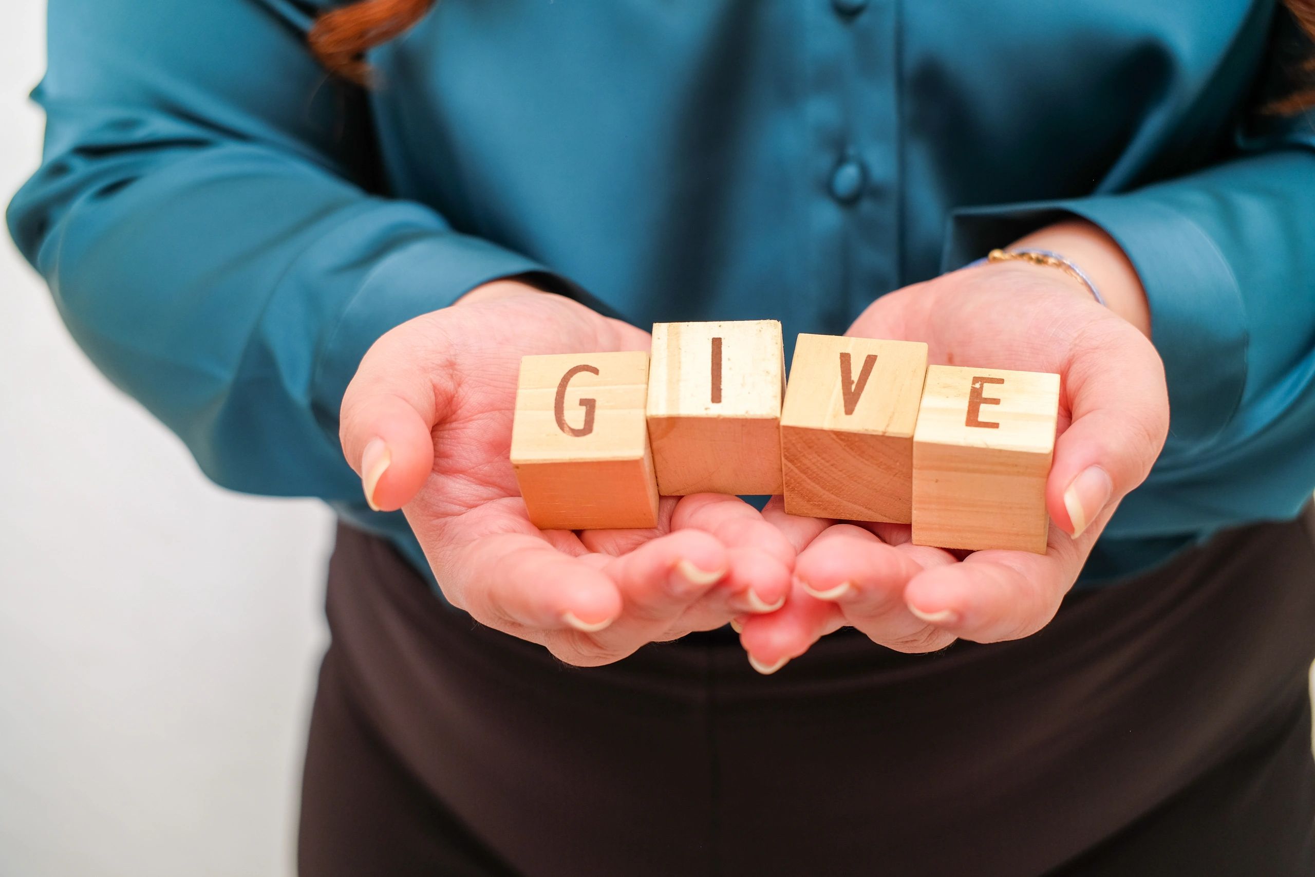 Hands holding blocks spelling GIVE.