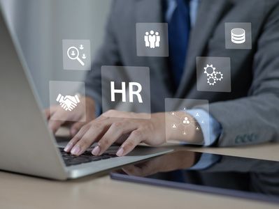 Businessman using laptop with HR icons floating.