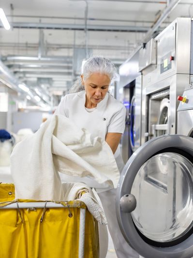 Woman loading laundry into a washing machine.