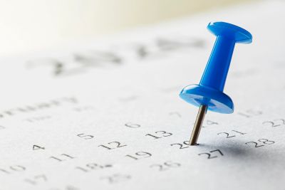 Blue pushpin marking a date on a calendar.