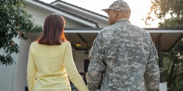Person in military uniform holding hands with a woman.