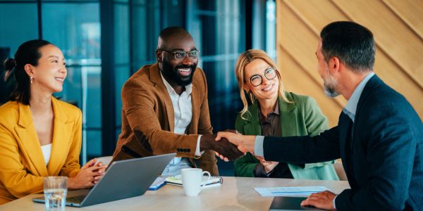 Businessmen and women shaking hands in a meeting.