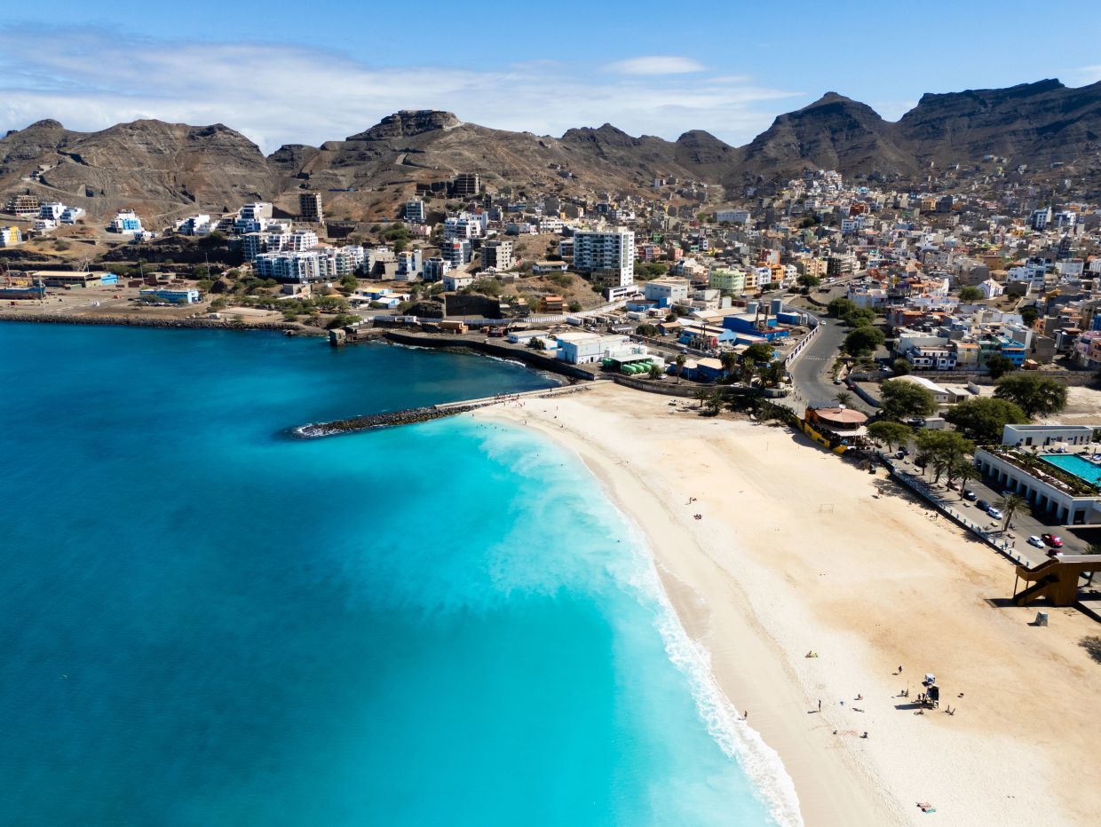 A coastal city with a sandy beach and clear blue water.