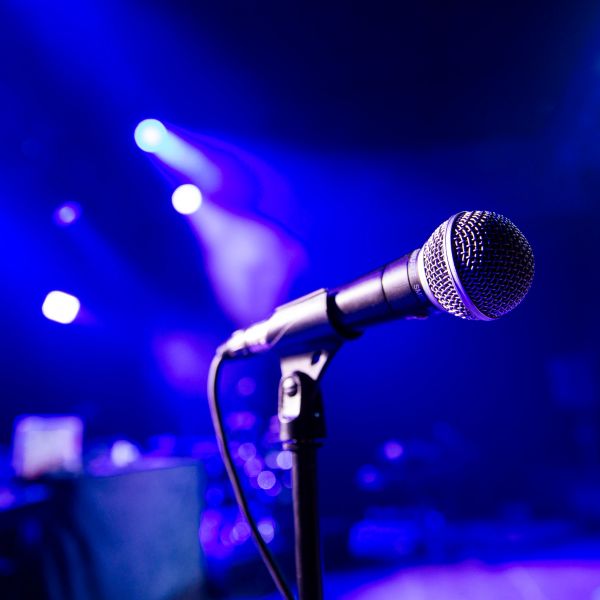 Close-up of a microphone on stage with blue lights.