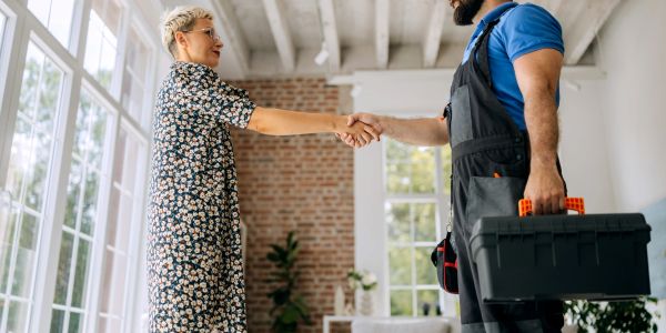 Woman shaking hands with a repairman.
