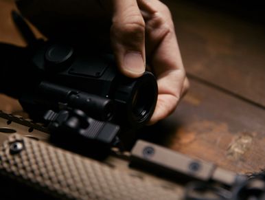 Person adjusting a riflescope on a firearm.